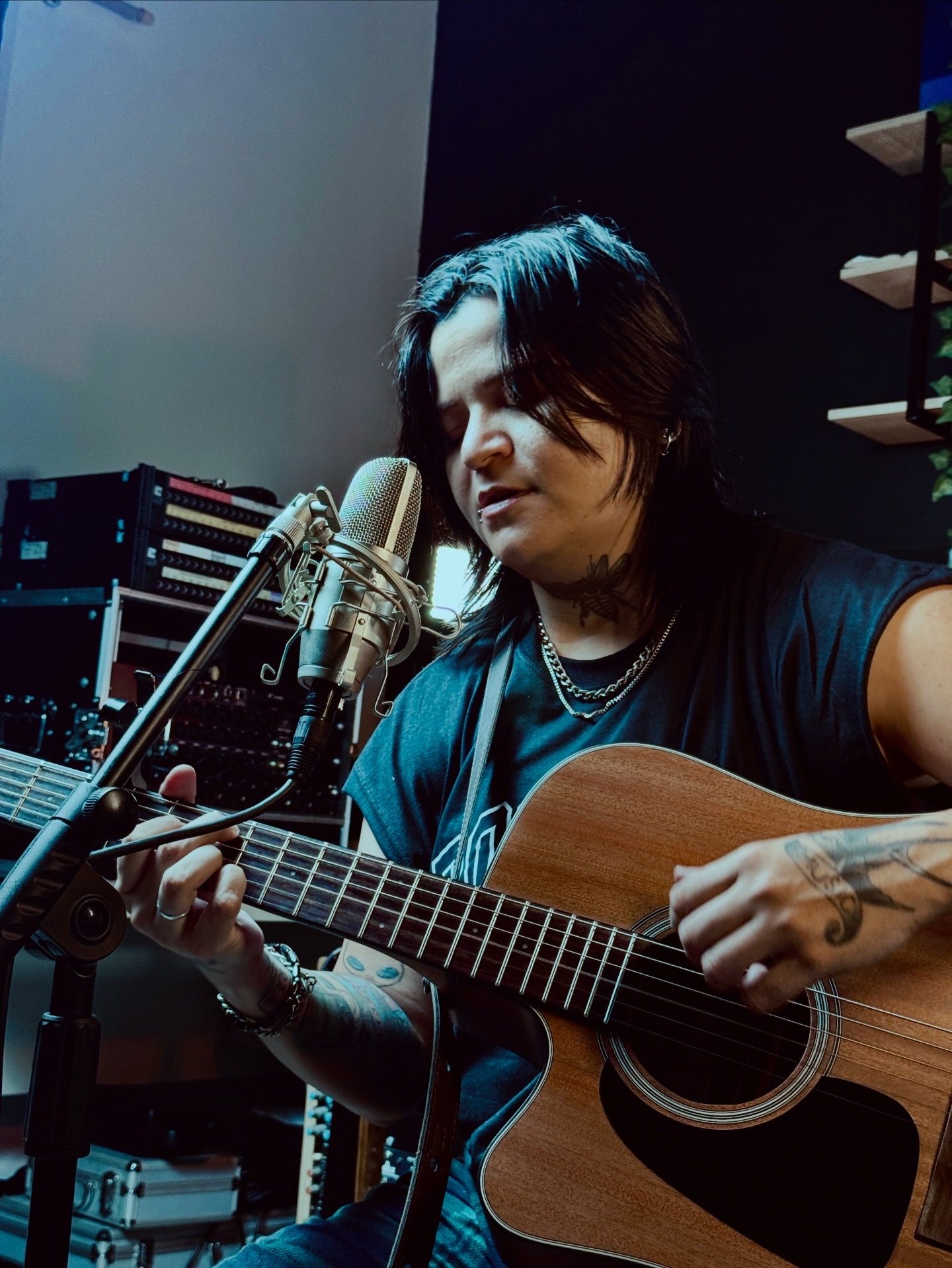 Artista cantando e tocando violão em captação audiovisual